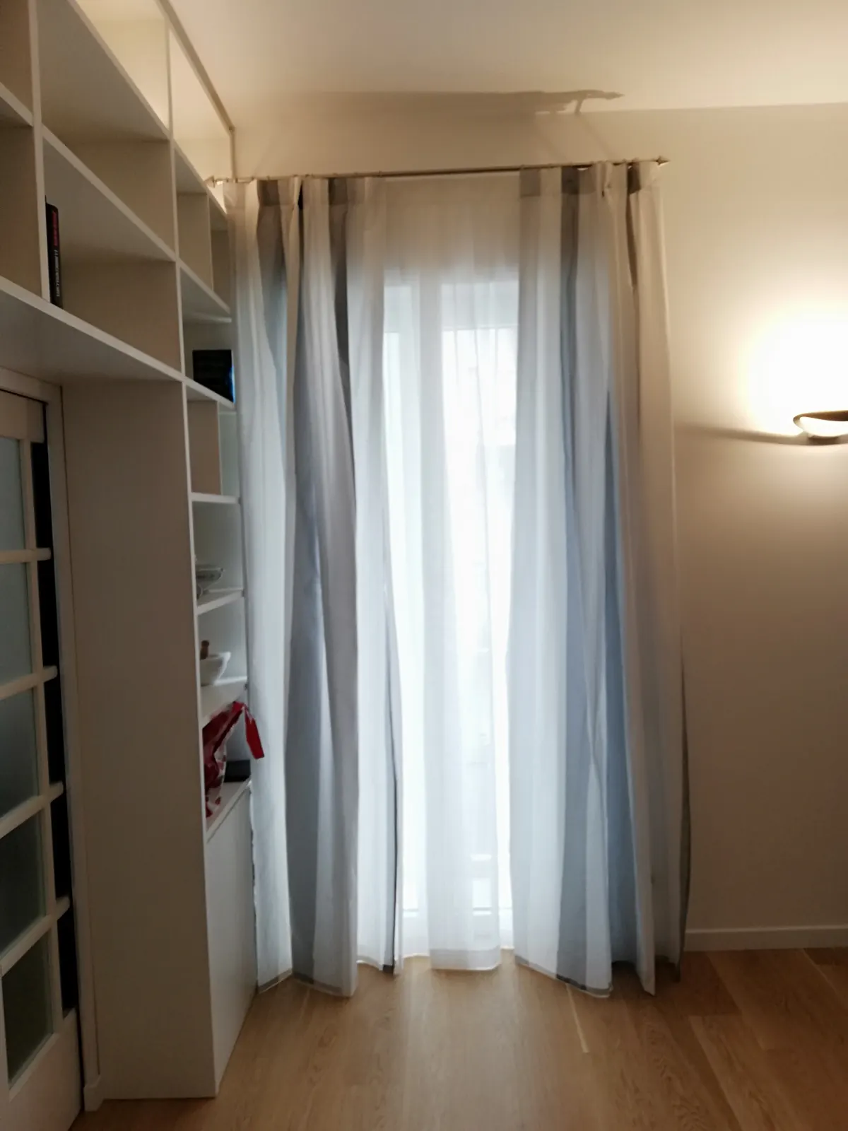 Tenda con velo bianco e tendaggio laterale accanto a una libreria